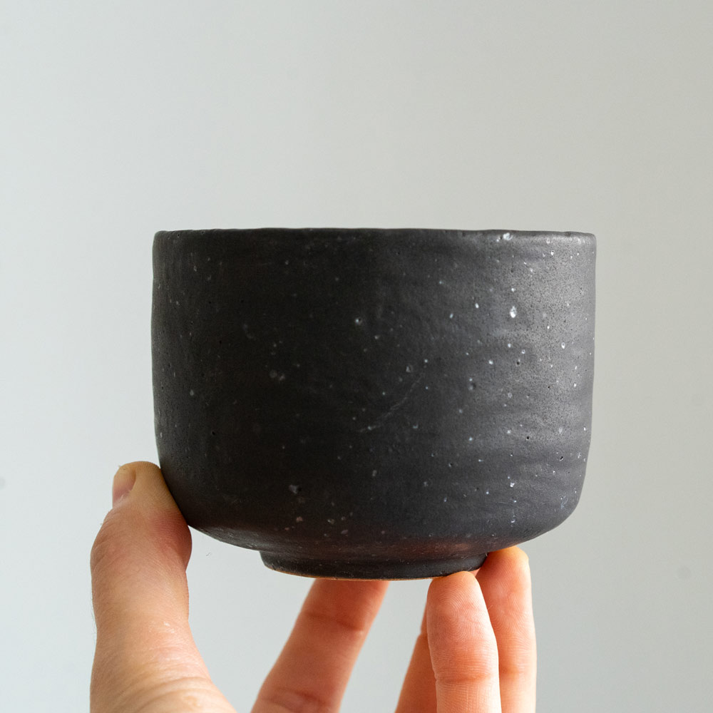 Handgemachte Keramik in verschiedenen Formen handgemachter Becher in matter schwarzer Glasur mit silbernen Sprenkeln