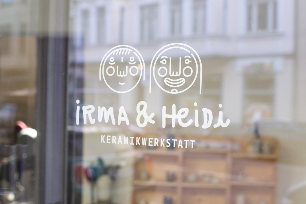 Kommt vorbei Beschriftung des Eingangs mit Irma & Heidi Logo und Blick in die Werkstatt
